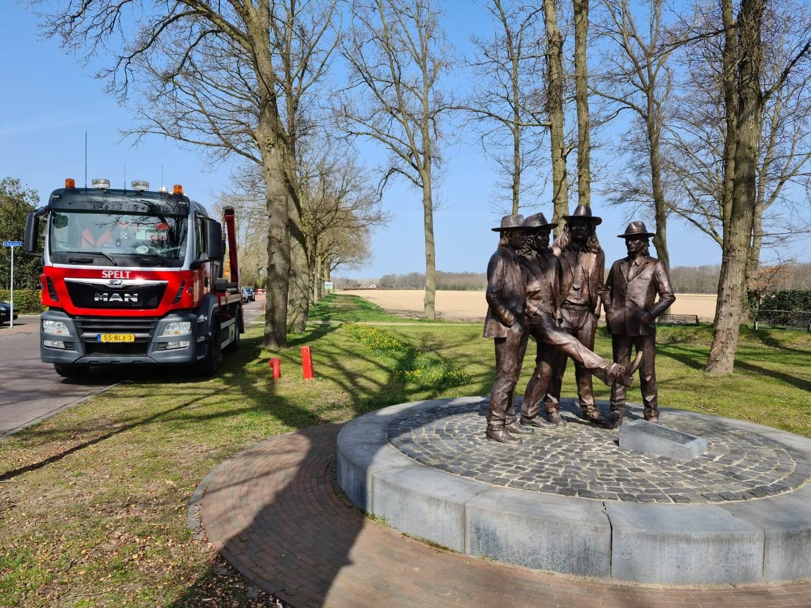 standbeeld van vier mannen en vrachtwagen spelt